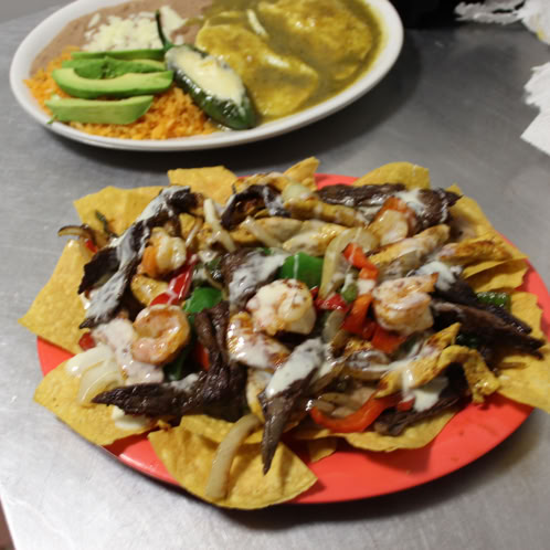A top view of assorted Mexican tacos with lime, cilantro, and fresh toppings.